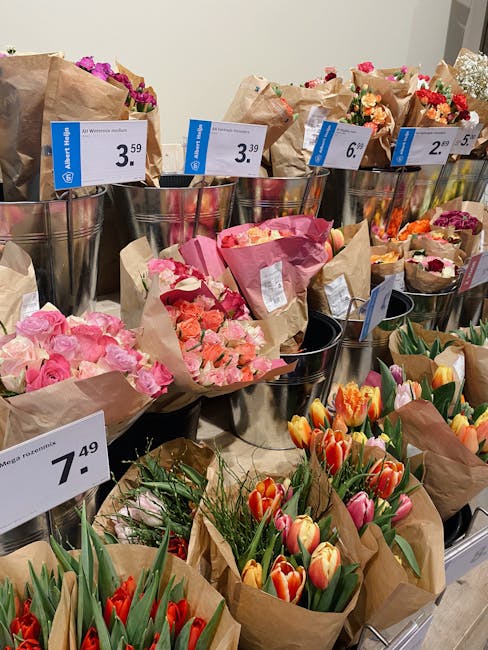 A display of various floral bouquets and arrangements at a florist shop, showcasing an assortment of fresh flowers including pink roses, orange and red tulips, and mixed seasonal blooms, all wrapped i