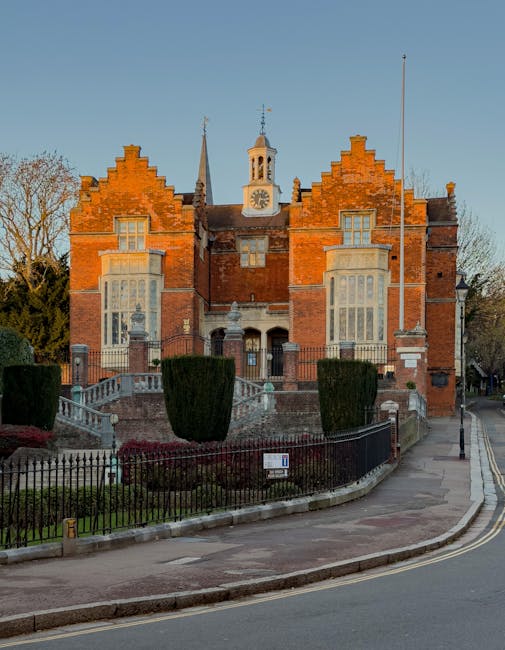 A detailed floral arrangement featuring a bouquet of fresh flowers held in hands, positioned in front of a historic red brick building with a clock tower, set on a raised platform with decorative ston
